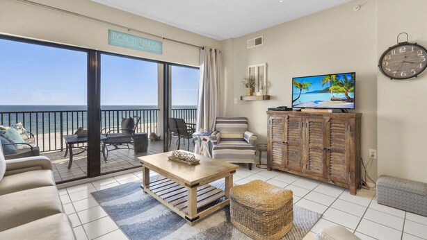 Uma sala ampla com varanda vista para o mar, televisão e um armário de madeira.