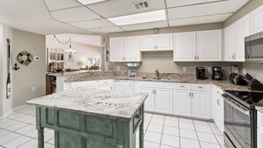 Cozinha moderna com armários brancos, bancada de granito e eletrodomésticos de aço inoxidável.
