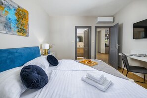 Une chambre d’hôtel avec un lit, un bureau, une chaise, une télévision et un tableau au mur.