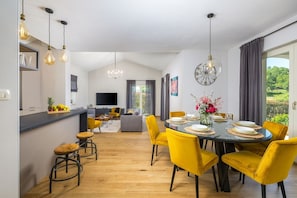 A modern kitchen with a dining area, yellow chairs, a round table, and a chandelier. - Villa Bartol with private pool, table tennis, darts (Trviz)