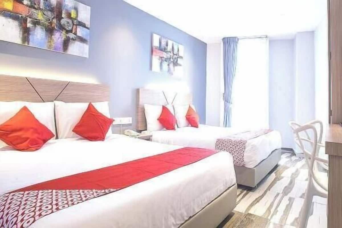 Une chambre d’hôtel avec deux lits, un bureau, une chaise, une télévision et des œuvres d’art accrochées aux murs.