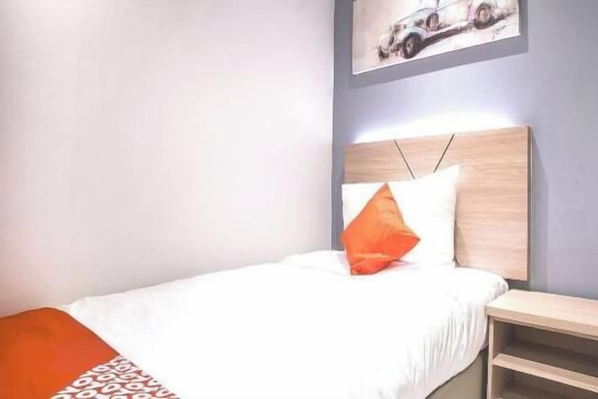Ein Schlafzimmer mit einem Bett, einem Nachttisch und einem an der Wand befestigten Regal.