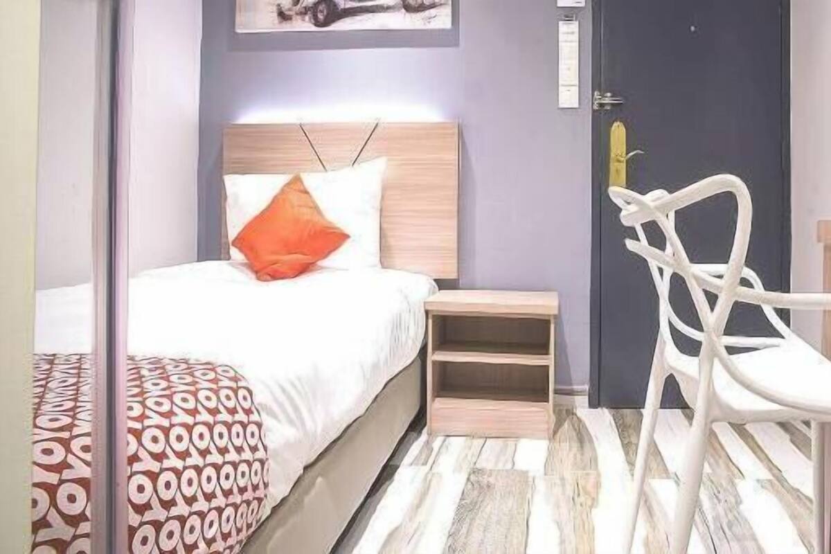 Une chambre à coucher avec un lit, une table de chevet, une chaise et une porte.