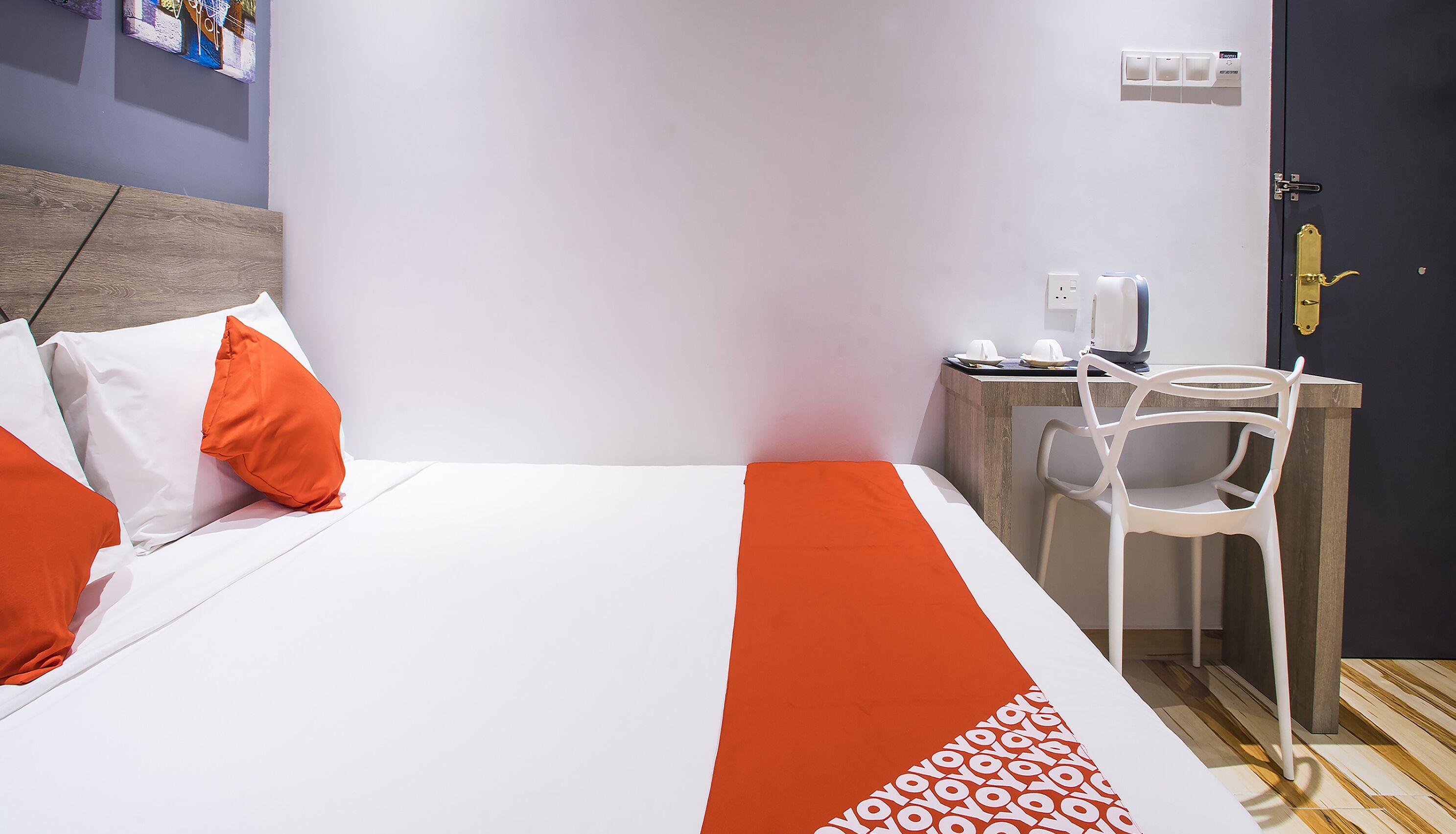 Een hotelkamer met een bed, een bureau, een stoel en een deur.