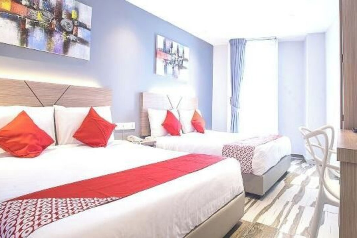 Une chambre d’hôtel avec deux lits, un bureau, une chaise, une télévision et des œuvres d’art accrochées aux murs.