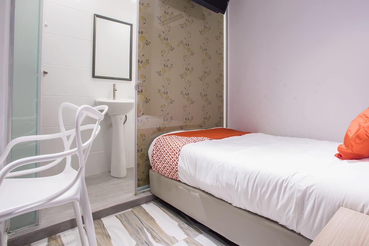 Une chambre à coucher avec un lit, une chaise blanche, un lavabo et un miroir.