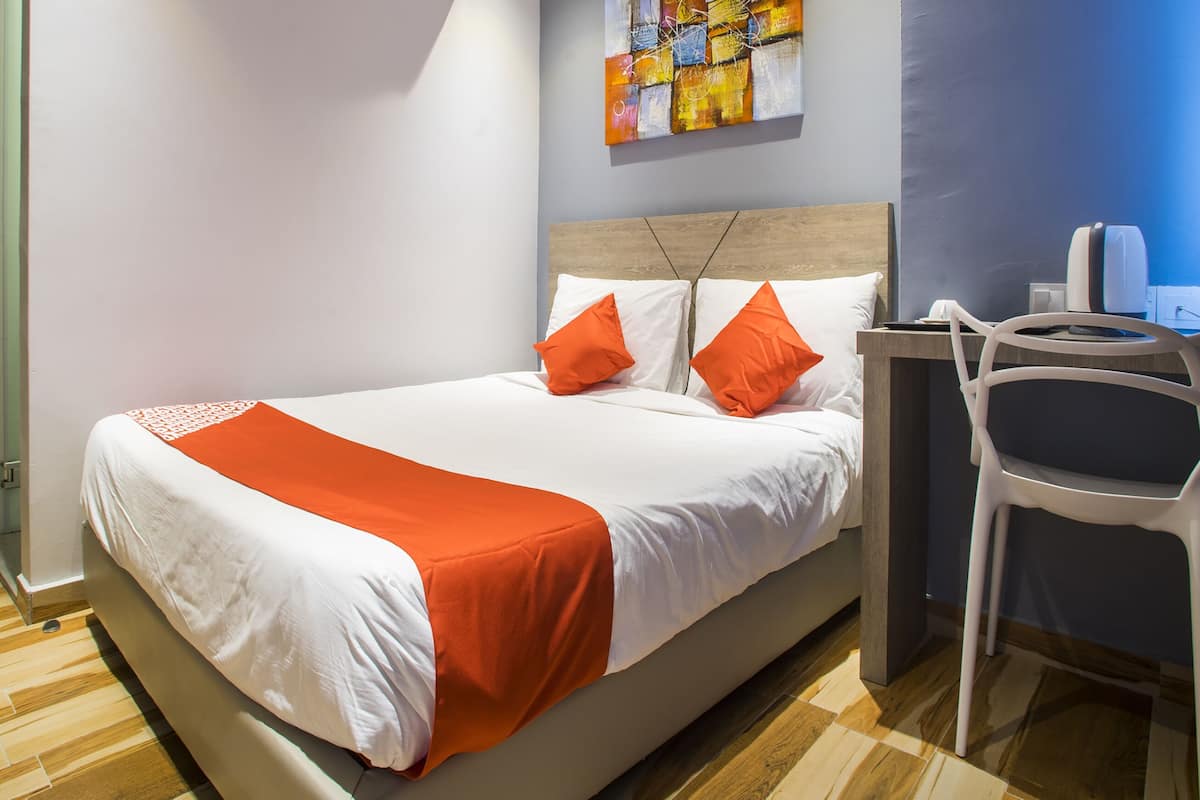 Une chambre d’hôtel avec un lit, un bureau, une chaise et un tableau au mur.