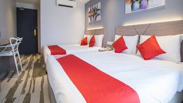 Habitación de hotel con dos camas, ropa de cama roja y blanca, un escritorio y una silla.