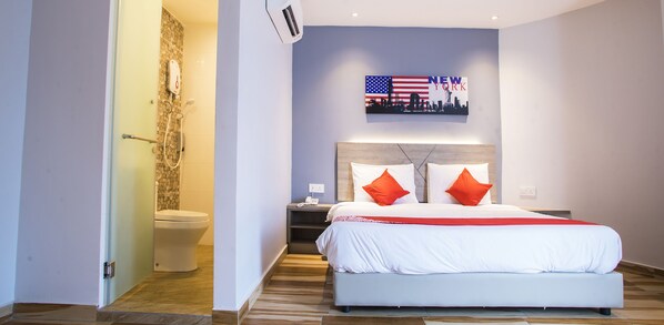 A hotel room with a bed, a nightstand, a wall-mounted TV displaying 'NEW YORK', and a shower area.