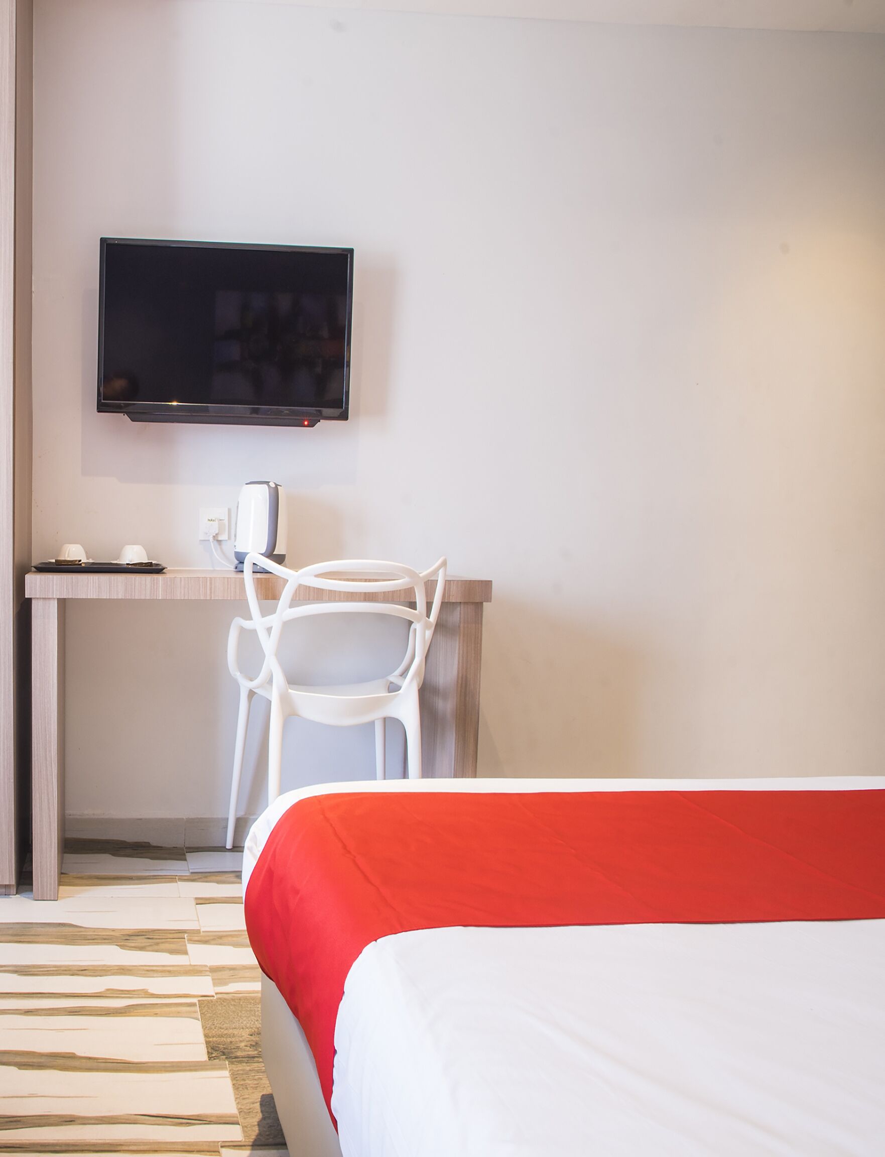 A hotel room with a bed, a desk, a chair, a television, and a coffee maker.