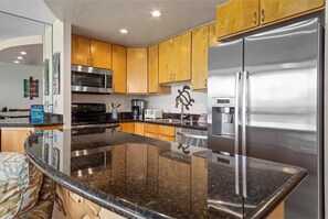 Una cocina moderna con electrodomésticos de acero inoxidable, armarios de madera y encimera de granito.