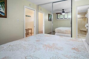 Un dormitorio con cama, un taburete pequeño, un espejo y zona de ducha.