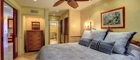 Ein Schlafzimmer mit einem großen Bett, einem Deckenventilator, einer Kommode und einem Bild an der Wand.