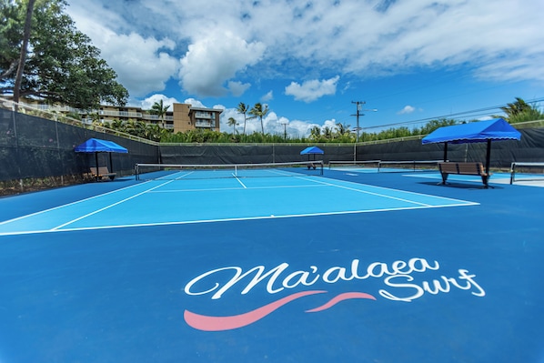 Un court de tennis extérieur doté d’un revêtement bleu et d’un filet.