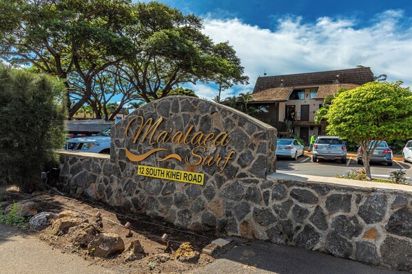 Señal de piedra con 'Maddens Surf' y '12 South Kihei Road' que indica una ubicación.