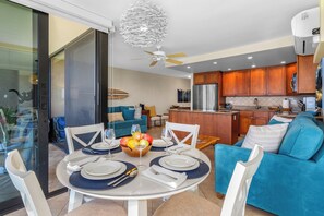 A modern kitchen with wooden cabinets, a central island, and a dining area with a round table set for four.
