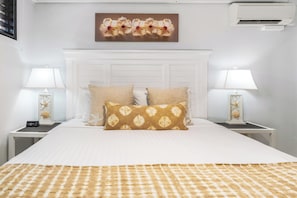 Quarto bem arrumado com uma cama grande, duas mesas de cabeceira com luminárias e um objeto decorativo na parede acima da cama.