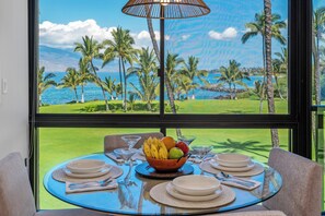 Une table à manger donnant sur un paysage tropical grâce à une grande fenêtre.