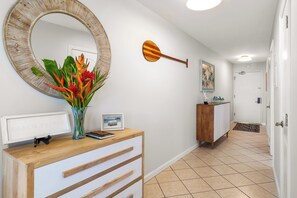 Un couloir avec une console en bois, un miroir rond, une décoration murale en forme de pagaie en bois et une porte au fond.