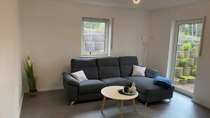 A modern living room with a grey sectional sofa, a small round coffee table, and a potted plant. - Apartment in the countryside near Koblenz, Apartment im Grünen bei Koblenz (Vallendar)