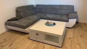 Un canapé d’angle gris avec une petite table d’appoint placée devant.