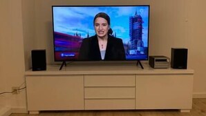 Un téléviseur posé sur un meuble blanc, avec deux haut-parleurs de chaque côté.
