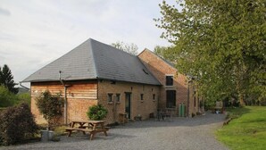 A brick building with a sloped roof, a gravel driveway, and a picnic table. - L'Ermite (Saint-Algis)