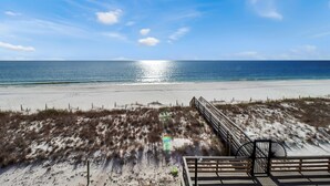 A beach with a wooden boardwalk and a chair.