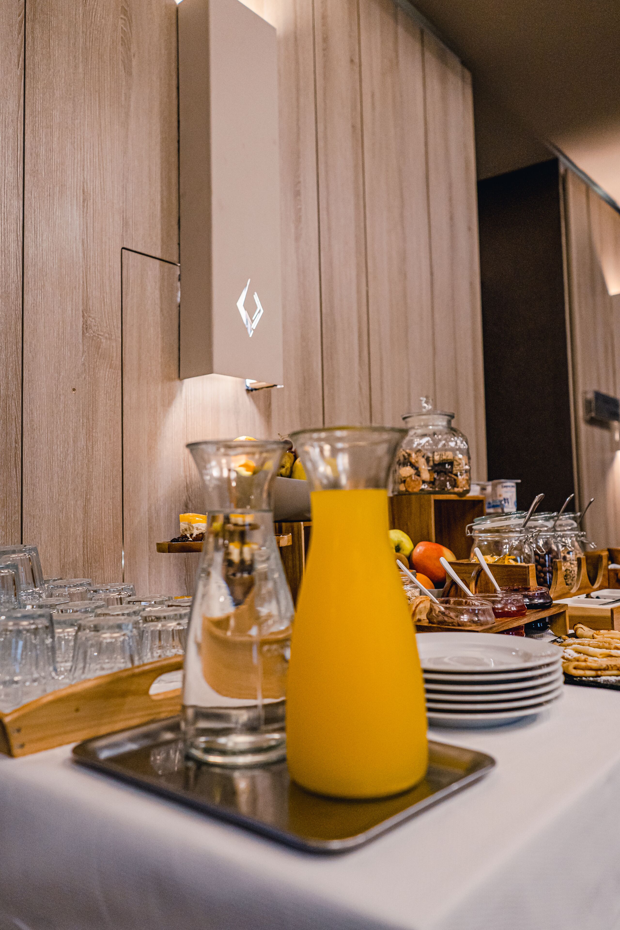 A buffet setup with a variety of food items and a yellow pitcher of juice.