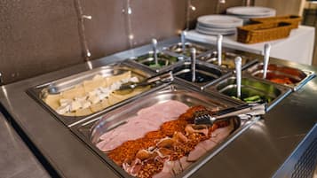 Buffet com diversos alimentos, incluindo frios e queijos.