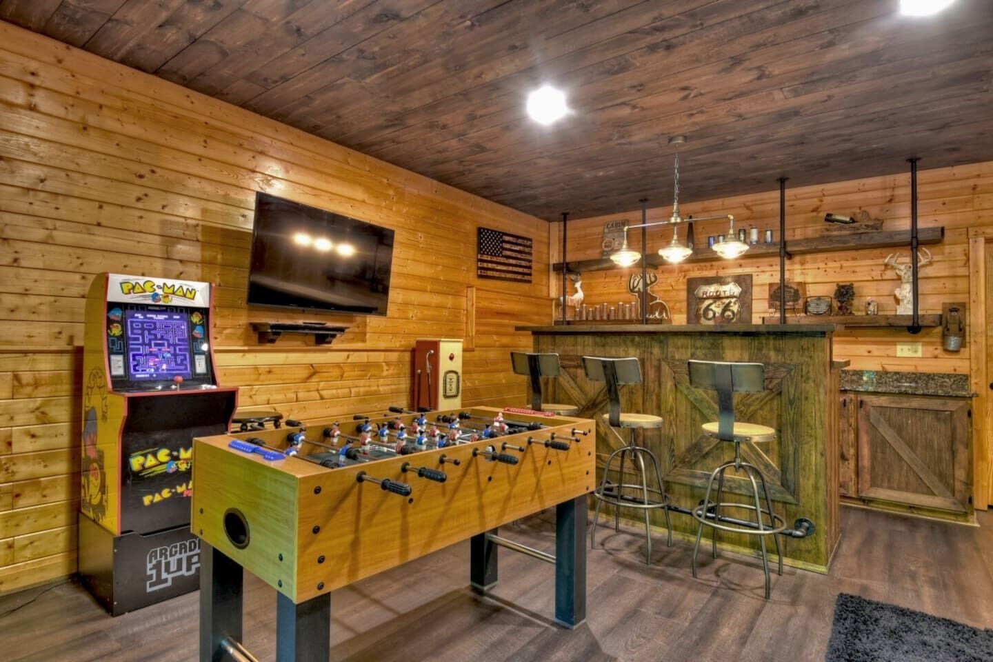 Een gezellige kamer met een tafelvoetbaltafel, een televisie en een bar met krukken.