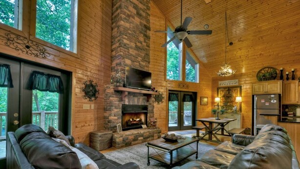 A cozy cabin interior with a fireplace, leather sofas, a dining table, and a kitchen area. - Escape to Tranquility: Sleepy Hollow Cabin Retreat (Ellijay)