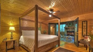A four-poster bed in a log cabin bedroom with a fireplace and a view of the outdoors. - Escape to Tranquility: Sleepy Hollow Cabin Retreat (Ellijay)