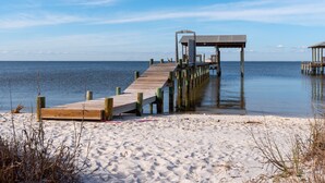 A wooden pier extending into calm waters, with a covered structure at the end.