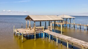 A wooden pier with covered structures extending into calm water, under a clear sky.