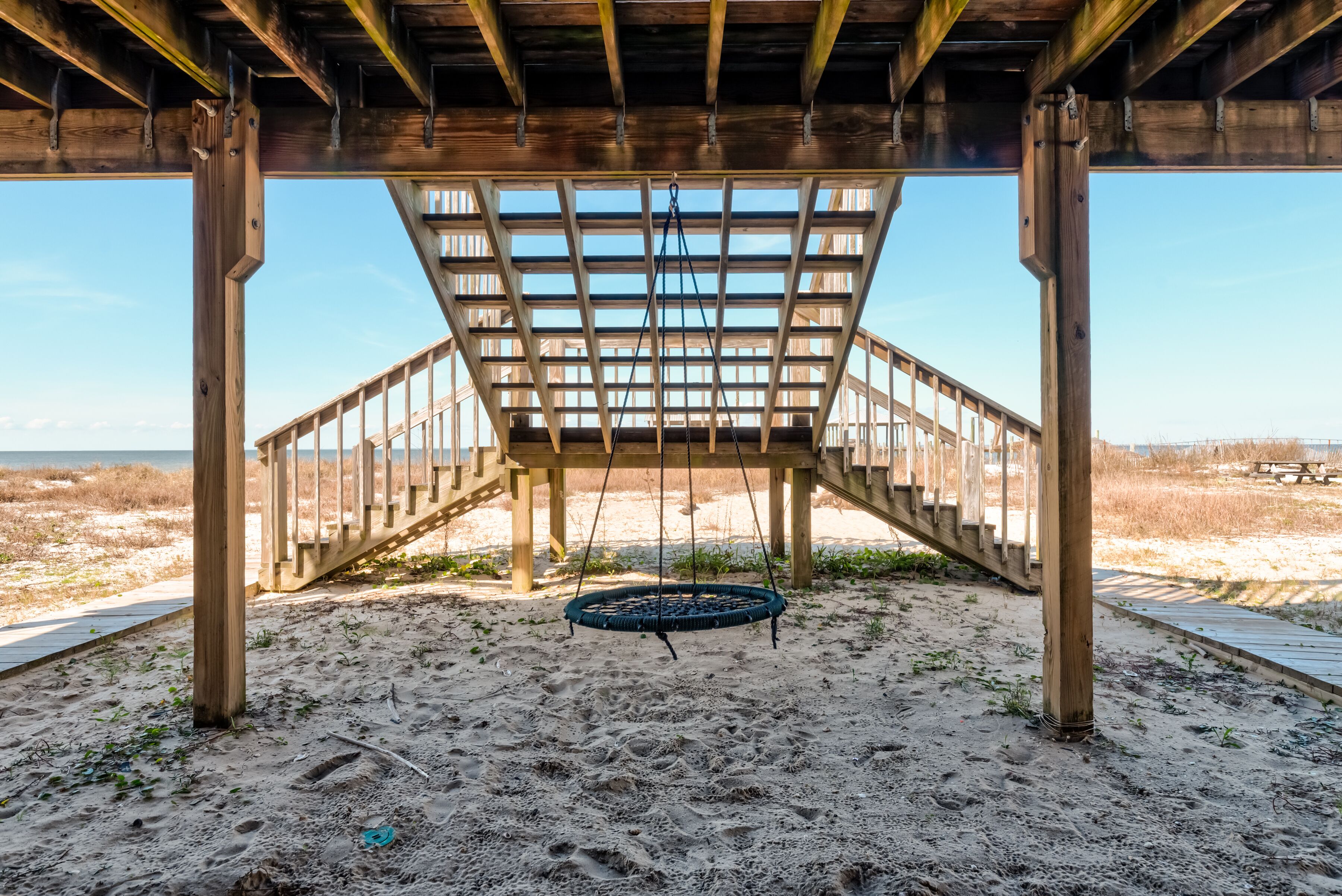 A wooden structure with a staircase leading to a beach area.
