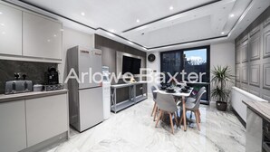 A modern kitchen with a dining area, marble flooring, and a large window. - Hackney Suites - Triple En-suite Room (F2) (Greater London)