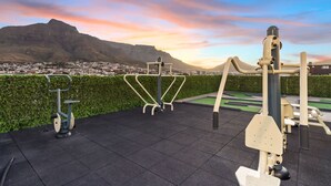 Outdoor exercise equipment with a cityscape and mountains in the background.