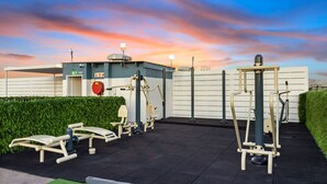 Outdoor exercise equipment, a covered area, and a building with a sign.