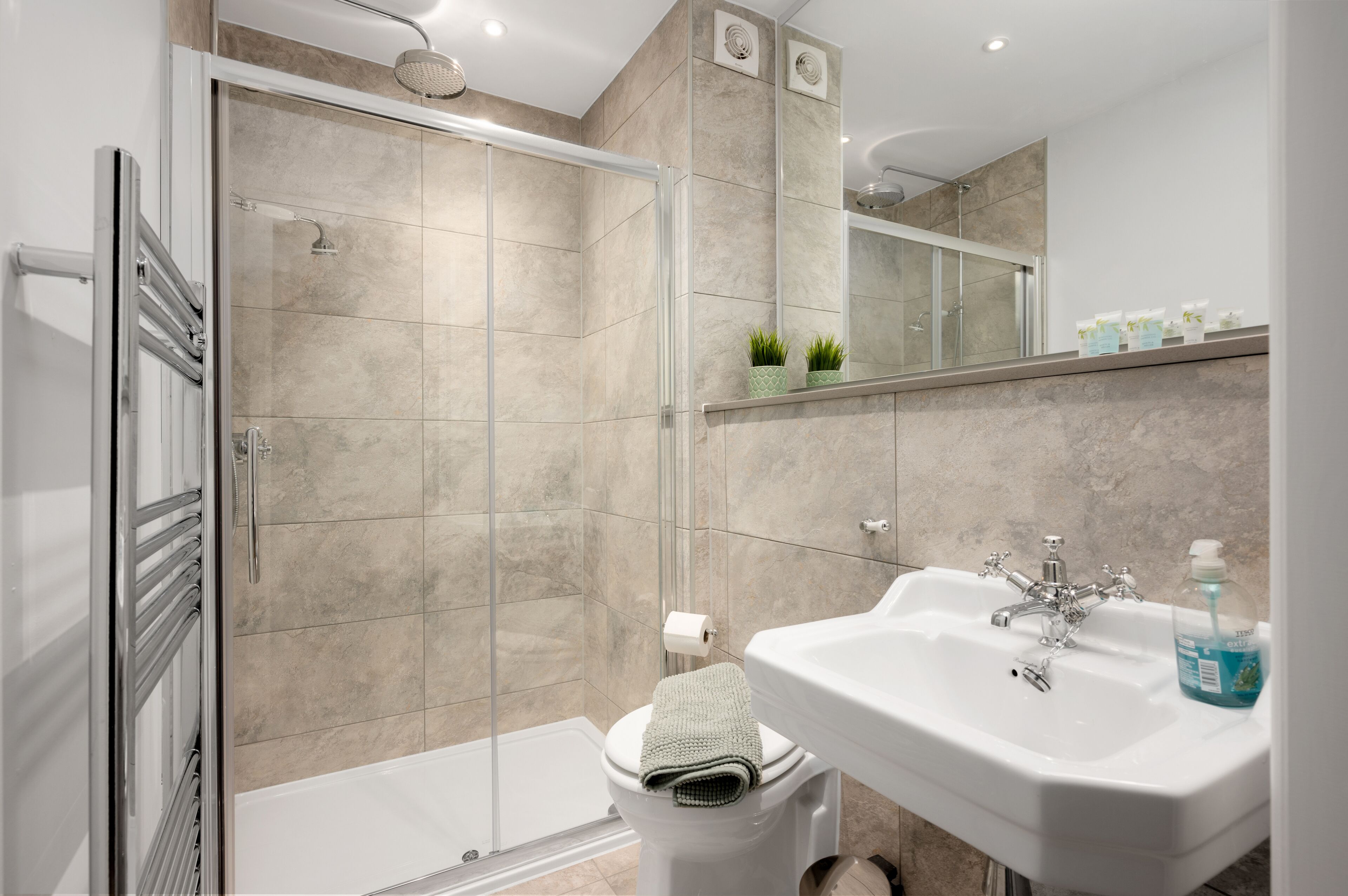 A modern bathroom with a glass shower enclosure, a white sink, and a toilet.