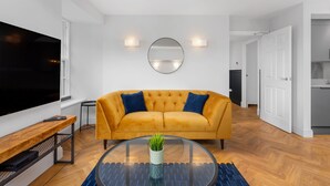 Ein modernes Wohnzimmer mit einer Couch, einem Fernseher und einem runden Couchtisch mit Pflanze.