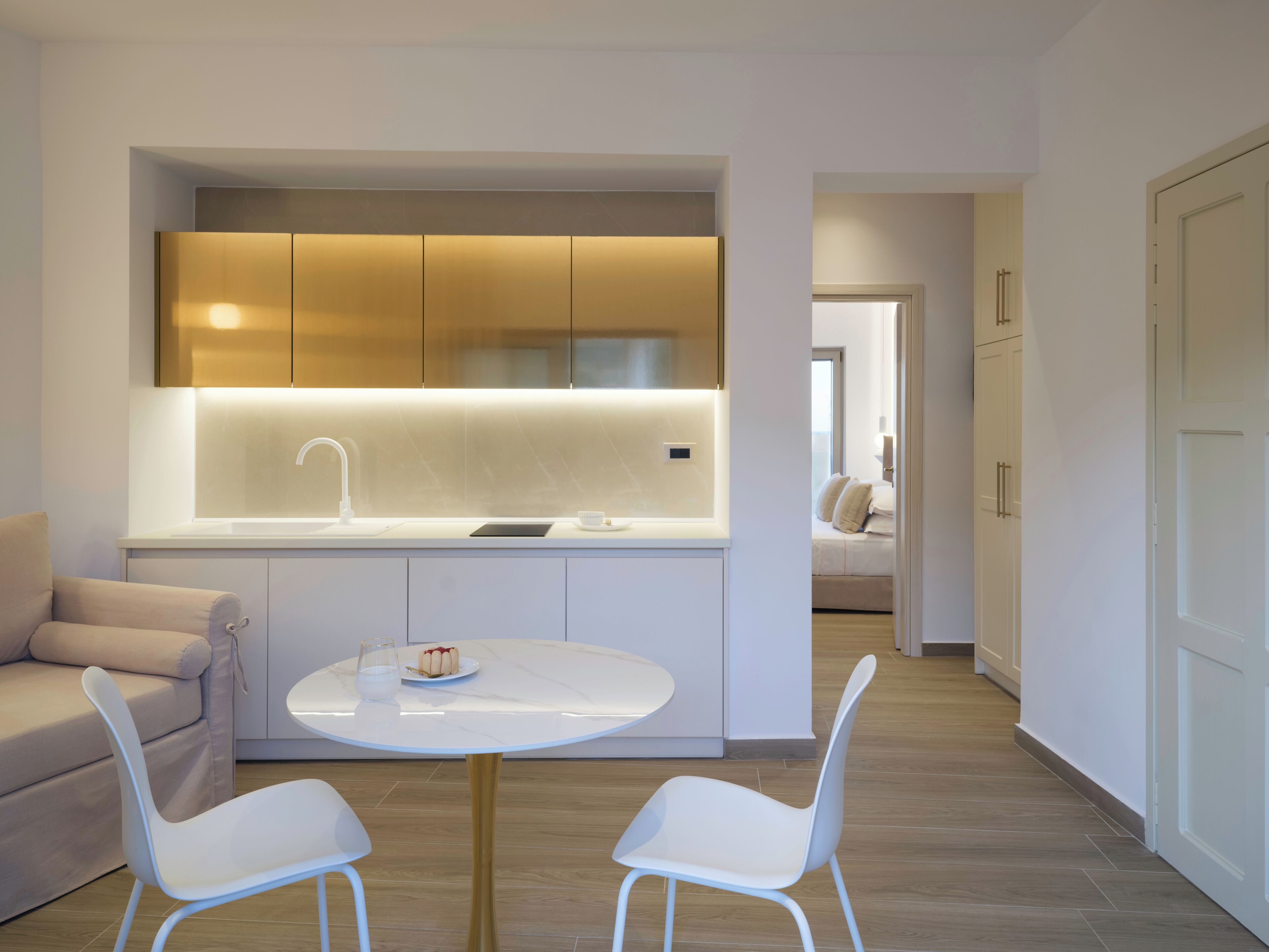 Une cuisine moderne avec des meubles blancs, une table de salle à manger ronde et deux chaises blanches.