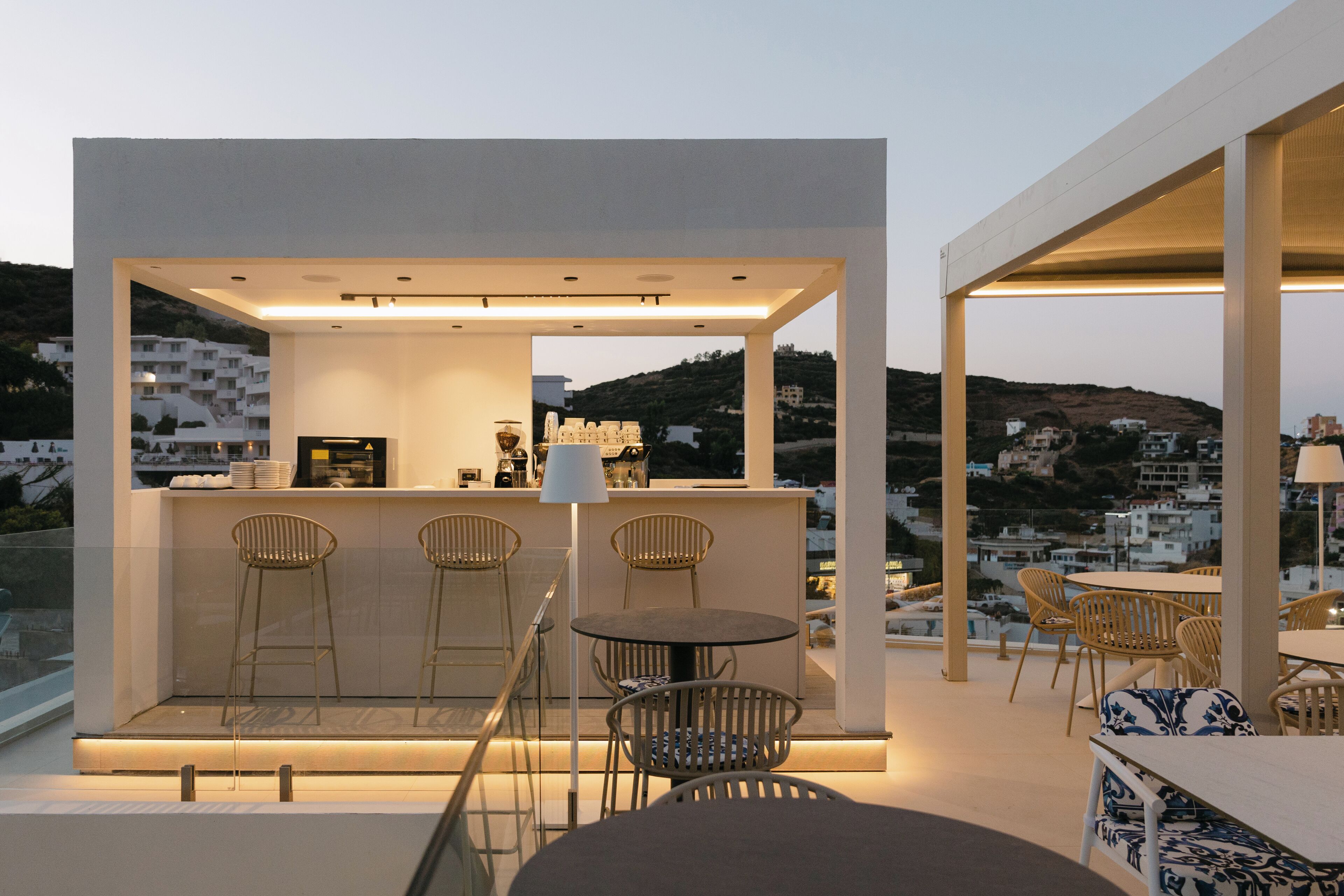 A rooftop bar with a bar counter, stools, and tables.