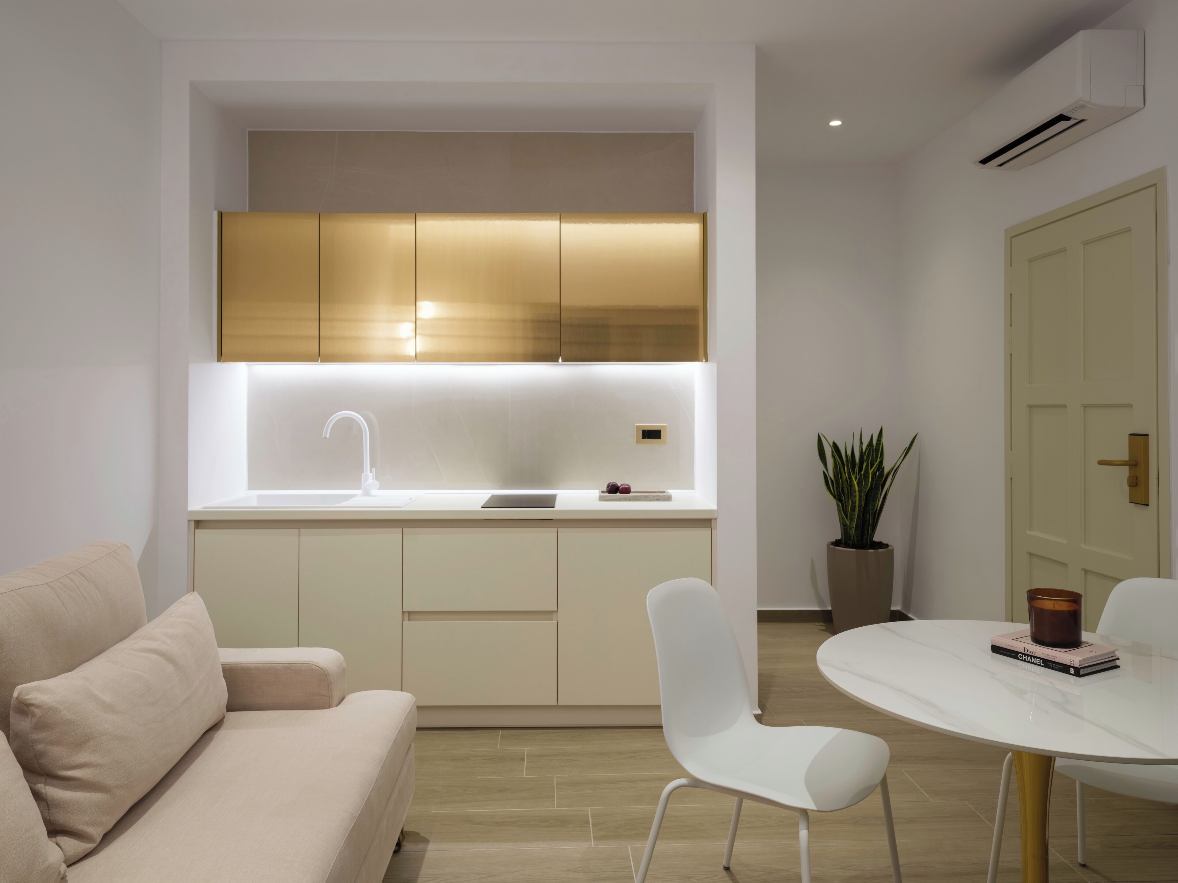 A modern kitchen with a built-in oven, a white sink, and a dining area with a white table and chairs.