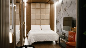 A modern hotel room with a large bed, wooden paneling, a marble wall, and a television. - Búho Kite Hotel Boutique (Juan de Acosta)
