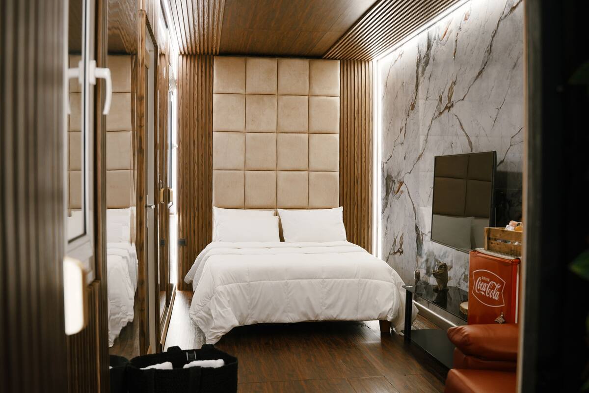 Ein modernes Hotelzimmer mit einem großen Bett, Holzwänden, einer Marmorwand und einem Fernseher.
