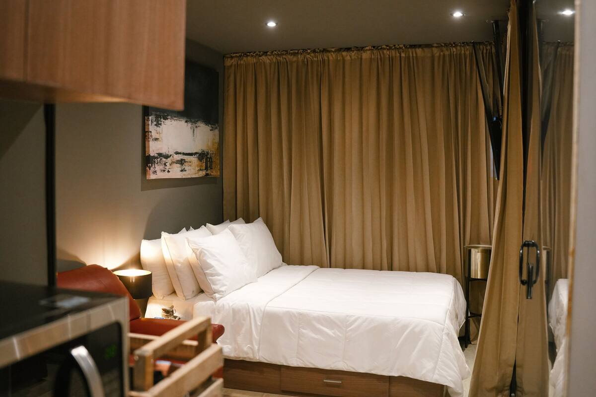 Ein Hotelzimmer mit Bett, Schreibtisch, Stuhl, Lampe und einem Bild an der Wand.