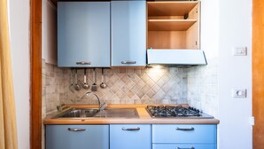 Una cocina compacta con armarios azules, una estufa a gas y un salpicadero de azulejos.