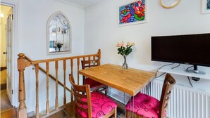 A dining area with a wooden table and chairs, a mirror, a clock, and a painting on the wall. - Charming Apartment with Private Patio & Oak Finishes near Clapham Station (London)