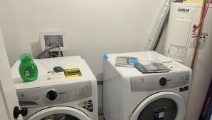 Two front-loading washing machines in a laundry room with a green bottle on the left and a white machine on the right. - A Home away from Home
 (Dieppe)